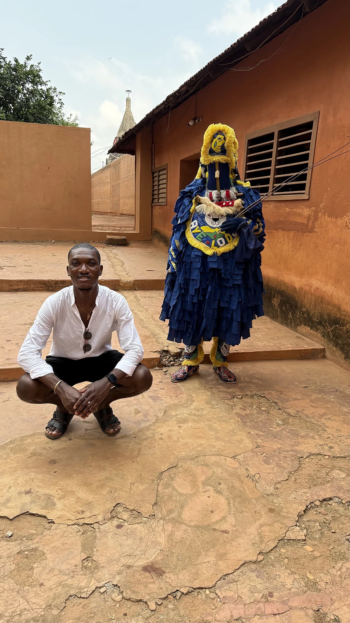 Traveller next to an Egungun masquerade
