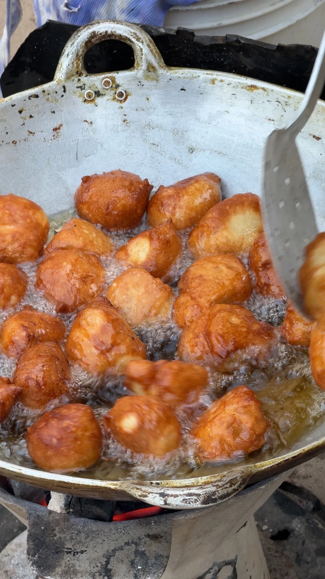 Beninese doughnuts frying over a wood fire